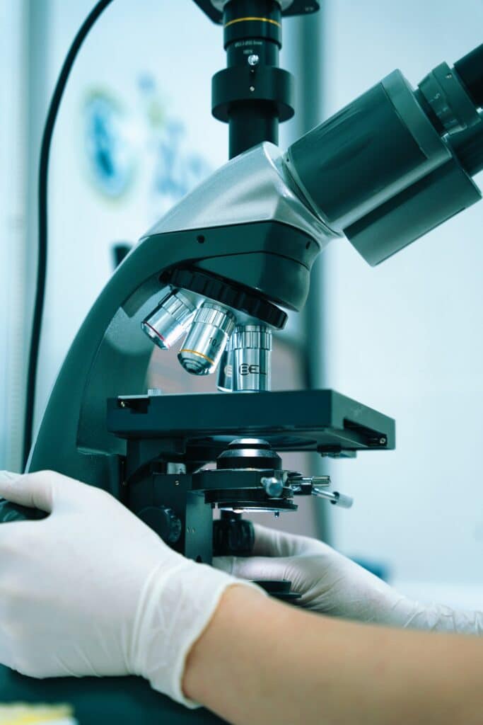 Technician using a lab microscope for specialized send-out blood work at Integria Precision Medicine